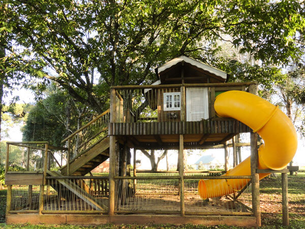 Uma imagem de um playground de crianças de dois andares feito em madeira tratada